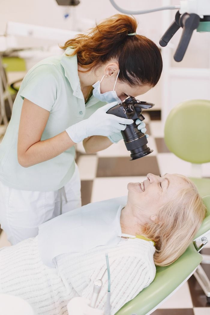 Dentist photographing patient in a dental office for treatment documentation.