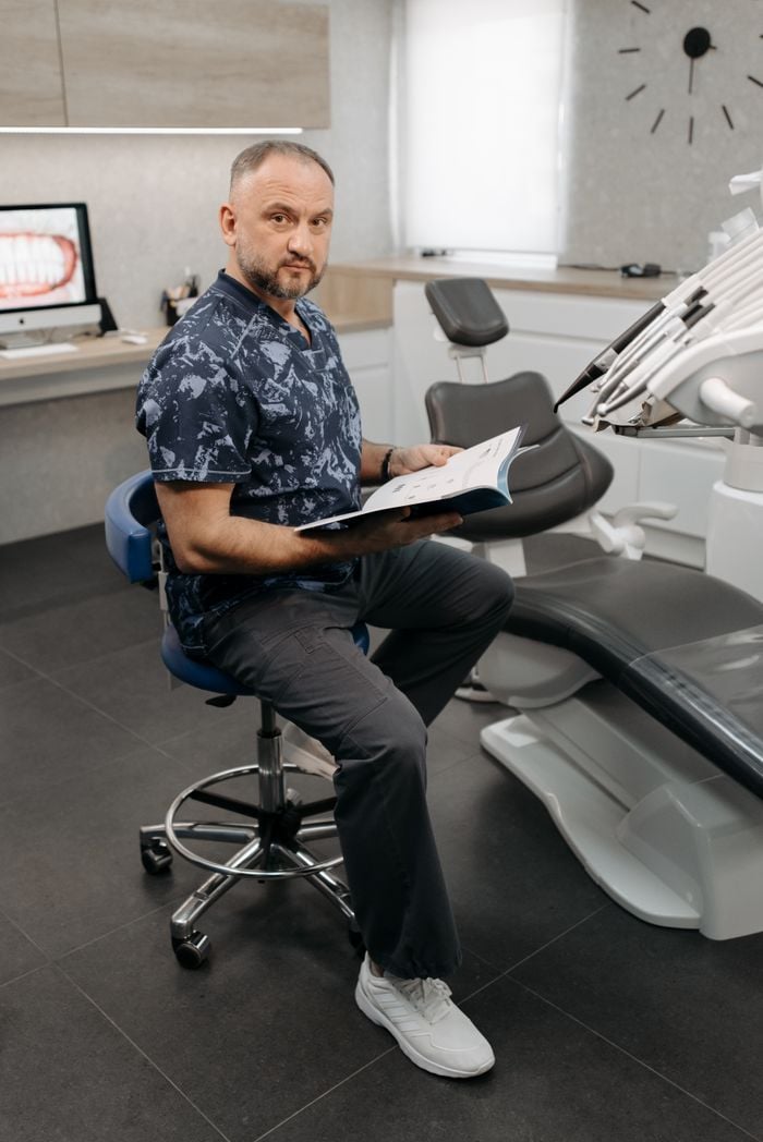 Mastering the First Impression: Your intriguing post title goes here Dentist seated in modern clinic reviewing patient records inside dental office.